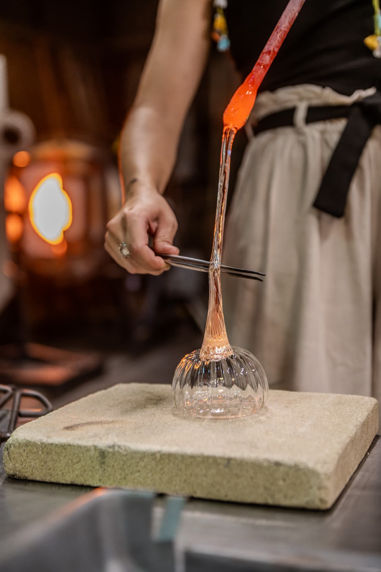Molten glass pumpkin being shaped on the marver