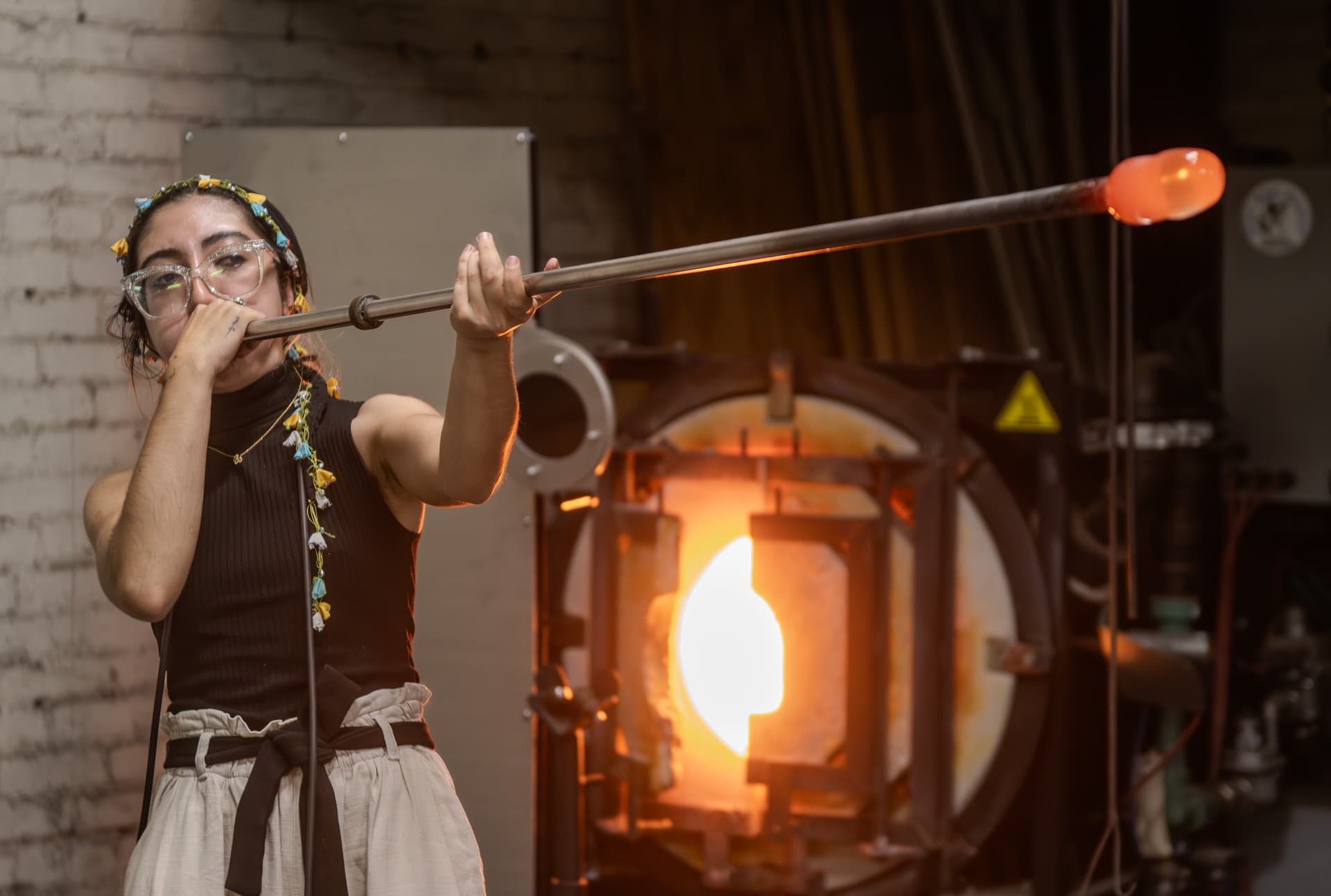 Zeinab Manesh blowing glass at the glowing furnace in her studio